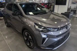 Renault Symbioz E-Tech Full Hybrid gris Cassiopé, vue 3/4 avant droit, avec calandre lumineuse et jantes bicolores.