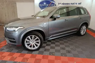 Vue de profil côté gauche d'un Volvo XC90 gris clair hybride rechargeable stationné en intérieur avec jantes alliage visibles.