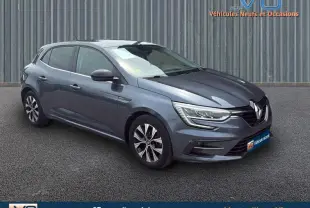 Renault Mégane IV Berline gris foncé vue 3/4 avant droit, jantes alliage 16 pouces et phares LED allumés.