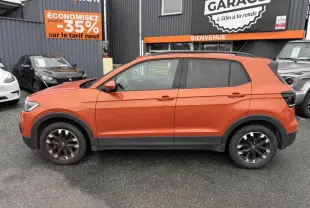 Profil droit d'un Volkswagen T-Cross 1.0 TSI 110 Active orange métallisé avec jantes Galway 16 pouces sur parking.
