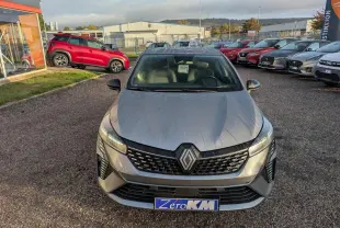 Renault Clio 2025 gris schiste vue de face, avec calandre noire et phares LED distinctifs, sur parking extérieur.