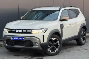 Dacia Duster beige Sandstone en 3/4 avant droit avec jantes alliage noires et barres de toit grises.