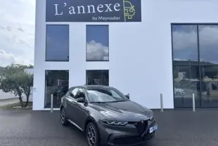 Alfa Romeo Tonale gris foncé métal en 3/4 avant droit devant un bâtiment blanc avec enseigne L'annexe by Meynadier.