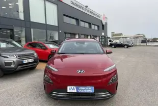 Vue de face d'un Hyundai Kona électrique rouge métal 2021 garé devant un centre de diagnostic automobile.