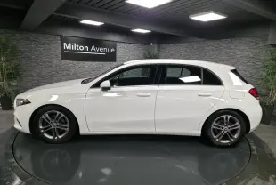 Profil côté gauche d'une Mercedes Classe A blanche 2019 avec jantes alliage 17 pouces dans un showroom.
