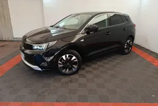 Opel Grandland noir vue 3/4 avant droit, avec jantes bicolores et phares LED allumés dans un garage.