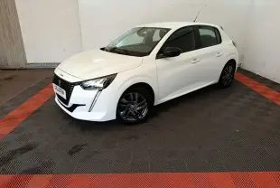 Peugeot 208 blanc vue 3/4 avant droit dans un garage avec jantes alliage foncé et rétroviseurs noirs.