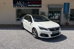 Peugeot 308 GT-Line blanche vue en 3/4 avant droit, avec jantes alliage et calandre noire distinctive.