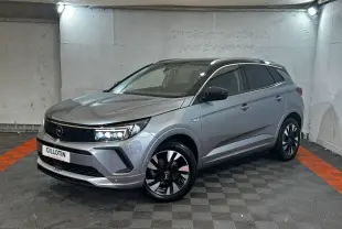 Opel Grandland gris clair en vue 3/4 avant droit, avec jantes noires et toit noir contrasté dans un garage.