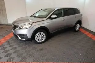 Peugeot 5008 gris clair vue 3/4 avant droit dans un garage avec sol noir et bandes rouges.