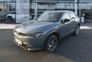 Vue 3/4 avant d'une Mazda MX-30 gris électrique 2021, avec ses phares ronds distinctifs et jantes noires.