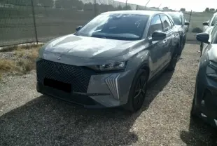 DS7 1.6 E-Tense gris laqué en 3/4 avant droit, avec calandre noire et feux LED distinctifs en forme de griffes.