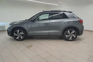 Vue de profil côté gauche d'un Volkswagen T-Roc 2025 gris Indium avec toit noir et jantes R-Line.