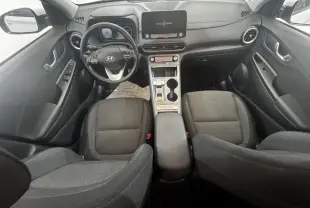Vue intérieure avant du Hyundai Kona électrique 2021, tableau de bord noir avec écran tactile central et sièges gris.