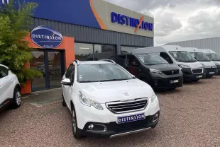 Peugeot 2008 blanc en 3/4 avant droit devant un concessionnaire Distinxion sous un ciel nuageux.