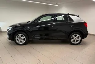 Profil côté gauche d'un Audi Q2 35 TFSI S Line noir mythic métallisé, intérieur clair, en showroom.