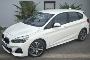BMW Série 2 Active Tourer 218dA blanc vue 3/4 avant droit avec jantes alliage 18 pouces et hayon électrique.