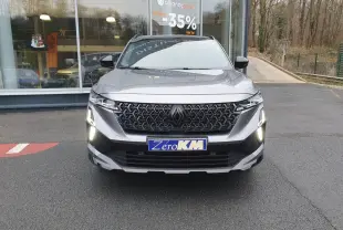 Vue de face du Renault Austral gris schiste avec calandre noire et feux LED allumés, toit panoramique noir visible.