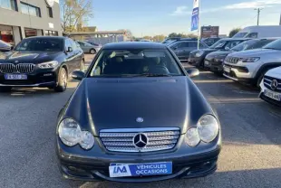 Vue avant d'une Mercedes Classe C Coupé Sport 220 CDI gris foncé métal stationnée en extérieur sur un parking.
