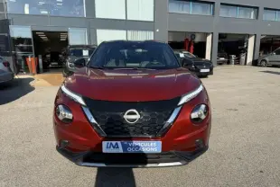 Vue avant d'un Nissan Juke 1.6 Hybrid 2024 rouge Fuji métal avec toit noir, calandre noire et détails chromés.