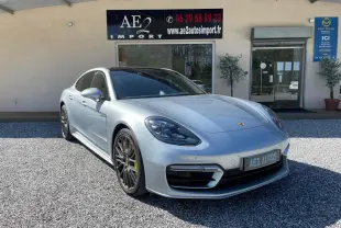 Porsche Panamera 4 V6 Hybrid gris vue 3/4 avant droit, jantes noires et étriers de frein verts visibles.