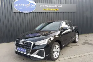 Audi Q2 35 TFSI S-Line noir mito metal en 3/4 avant droit, stationné devant un mur gris avec enseigne Distinxion.