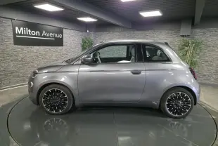 Profil droit d'une FIAT 500 Cabriolet électrique gris foncé avec jantes alliage bicolores en showroom.