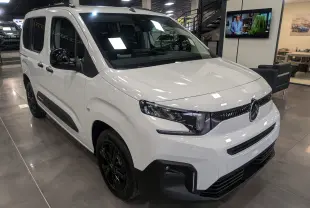 Vue 3/4 avant gauche d'un Citroën Berlingo blanc Glacier avec jantes noires et détails noirs contrastants en intérieur showroom.