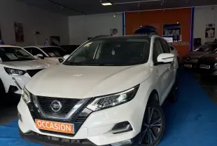 Nissan Qashqai blanc lunaire en 3/4 avant droit, avec jantes noires et plaque "OCCASION" en showroom.