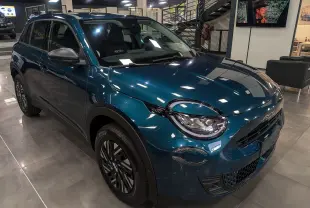 Vue 3/4 avant gauche d'un FIAT 600 Hybrid bleu Sea en showroom, avec phares ronds et jantes noires stylisées.