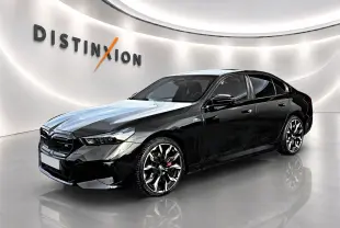BMW Série 5 i5 M60 noire vue en 3/4 avant droit avec jantes alu bicolores et calandre noire distinctive.