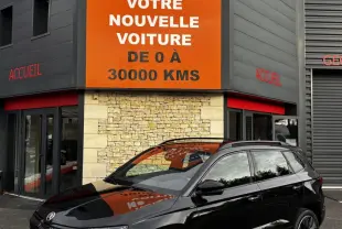 SKODA KAROQ noir vue 3/4 avant droit, garée devant un bâtiment avec panneau orange Distinxion.