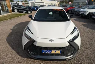 Vue avant d'un Toyota C-HR blanc 2024 avec calandre noire et feux LED, affichage prix sur pare-brise.