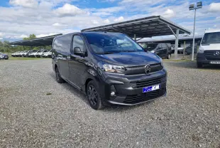 Vue 3/4 avant droit d'un Citroën Jumpy cabine approfondie gris titane avec jantes tôles 17 pouces sur parking gravillonné.