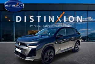 Vue 3/4 avant droit d'un Citroën C5 Aircross gris platinium avec toit noir, devant une vitrine Distinxion.