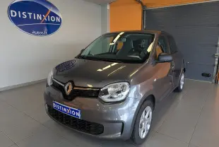 Renault Twingo III gris cassiopée vue 3/4 avant droit en intérieur avec logo Distinxion en arrière-plan.
