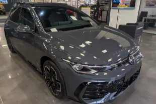 Vue 3/4 avant d'une Volkswagen Golf 1.5 eTSI R-Line gris dauphin avec jantes noires en concession.