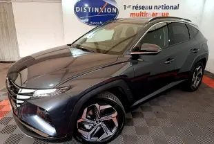 Vue 3/4 avant droite du Hyundai Tucson gris foncé 2022 avec jantes alliage et toit noir en intérieur showroom.