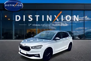 SKODA FABIA blanche vue 3/4 avant droit, jantes noires, devant vitrine Distinxion reflet ciel bleu.