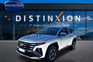 Hyundai Tucson blanc en 3/4 avant droit, avec calandre noire et jantes alliage distinctives devant showroom Distinxion.