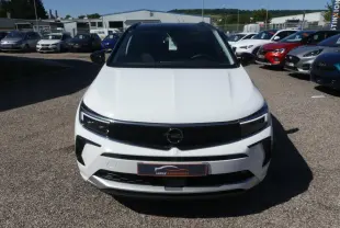 Vue avant d'un Opel Grandland blanc métallisé avec calandre noire brillante sur un parking extérieur.