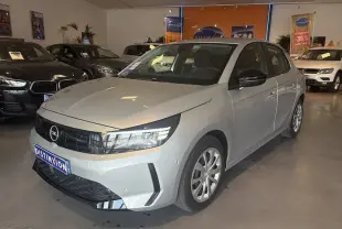 Vue 3/4 avant d'une Opel Corsa gris clair 2025 en concession, avec calandre noire et feux LED distinctifs.