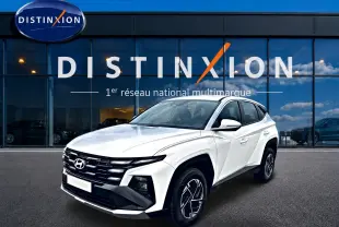 Vue 3/4 avant d'un Hyundai Tucson blanc 2026 devant une vitrine avec logo Distinxion.