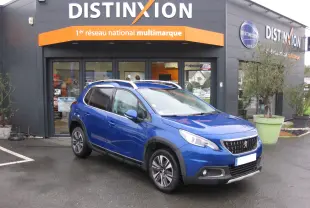 Peugeot 2008 bleu en 3/4 avant droit, finition Allure Business, stationné devant un garage Distinxion.