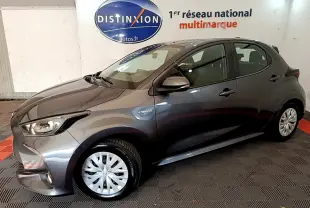 Toyota Yaris hybride gris clair vue de profil côté gauche, avec badge Hybrid et feux avant allumés.