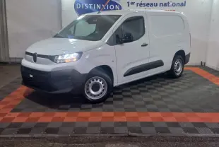 Vue 3/4 avant gauche d’un utilitaire Citroën Berlingo XL blanc avec phares allumés dans un showroom.