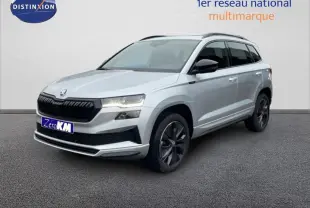 Vue 3/4 avant droite d'un Skoda Karoq argent avec barres de toit et jantes noires sportline.