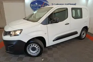 Vue 3/4 avant droit d’un utilitaire Peugeot Partner blanc avec jantes acier et protections noires sur les portes.