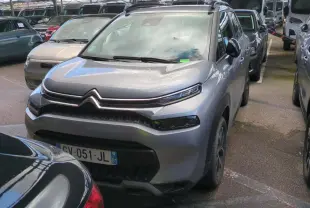 Citroën C3 Aircross gris foncé vue 3/4 avant droit avec barres de toit noir brillant en parking couvert.
