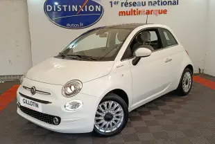 Vue 3/4 avant droite d'une Fiat 500 Dolcevita blanche, avec jantes multibranches et phares allumés en intérieur showroom.